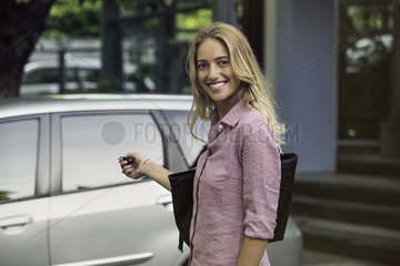 Woman approaching car with key in hand  smiling over shoulder