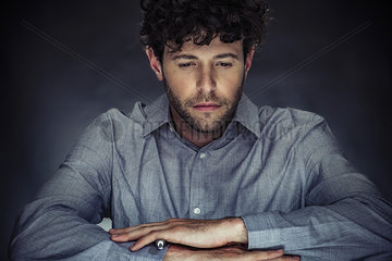 Man holding stylus with arms folded and eyes half-closed