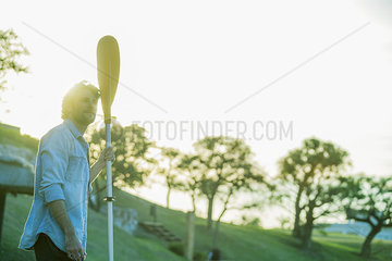 Man holding boat oar  backlit by sunlight