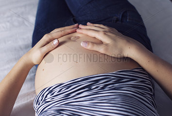 Pregnant woman with hands on bare stomach  cropped