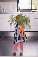Little girl holding large carrots in front of face