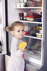 Little girl taking food out of refrigerator