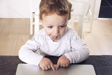 Little boy using touch pad on laptop computer