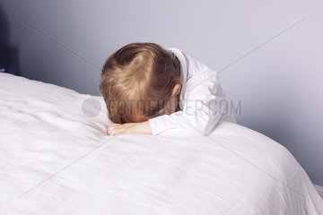 Little boy resting head on bed