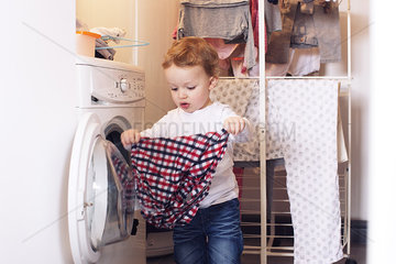 Little boy taking clothes out of dryer