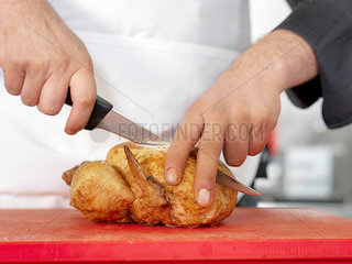 Chef cutting roasted chicken