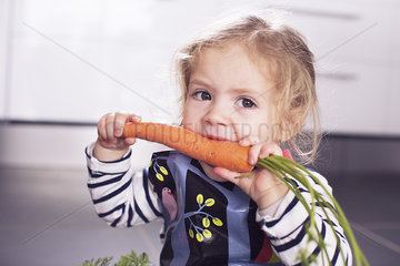 Little girl eating a carrot