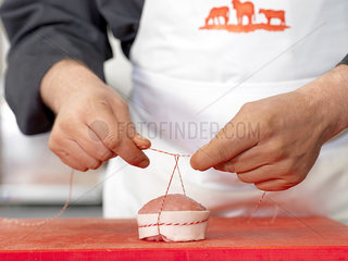 Butcher tying twine around meat cut  cropped