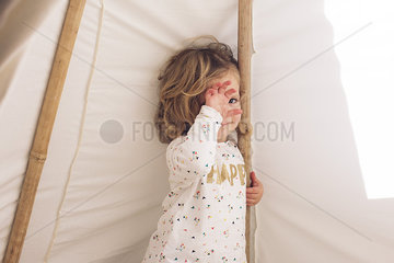 Little girl covering face with hand  smiling shyly