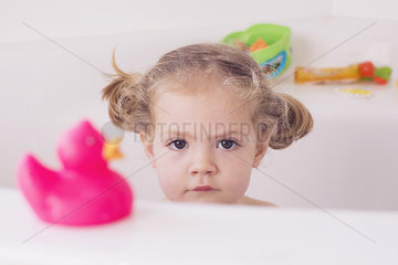 Little girl sitting in bath with unhappy expression  portrait