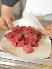 Butcher wrapping meat cubes in wax paper  cropped