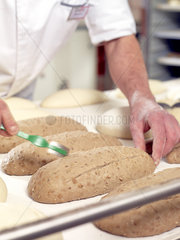 Baker scoring bread dough  cropped