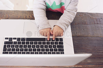 Child's hands on laptop computer keyboard