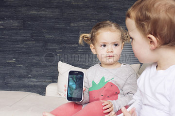 Little girl showing smartphone to her brother
