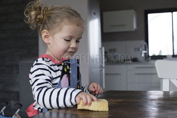 Little girl wiping table with sponge