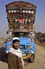 Pakistani Truckdriver in front of his decorated truck