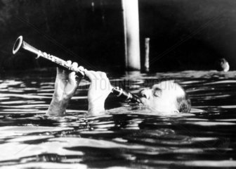 Mann spielt Klarinette im Wasser