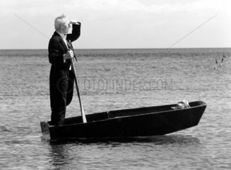 Mann in Frack steht in kleinem Boot
