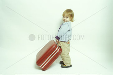kleines Kind sitzt auf einem Koffer