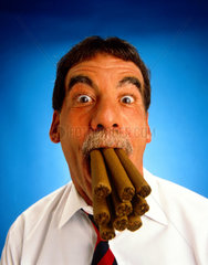 Mann mit neun Zigarren im Mund