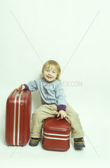kleines Kind sitzt auf einem Koffer