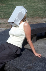 Frau mit Schuhkarton als Sonnenschutz