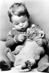 Kleinkind kuschelt mit Tigerbaby