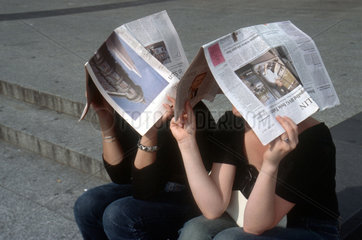 Jugendliche mit Zeitungen ueber dem Kopf