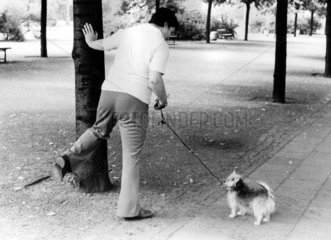 Frau macht einem Hund das Pinkeln vor
