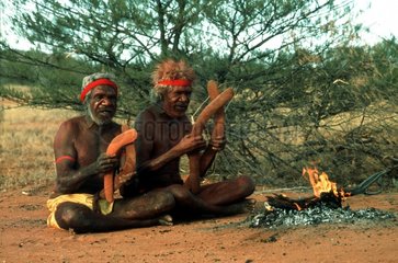 Aborigines mit Bumerang sitzen am Feuer