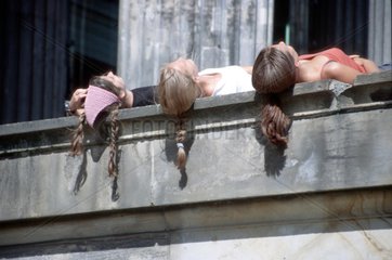 Haare sonnender Frauen haengen Mauer herunter