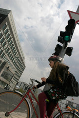 Berlin - Fahrradfahrerin mit Schutzhelm an eine Ampel