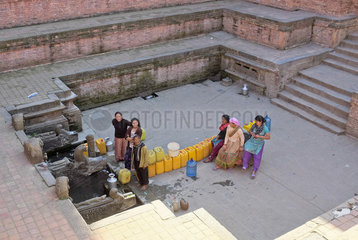 Frauen stehen an  um Wasser am Brunnen in die Kanister zu fuellen