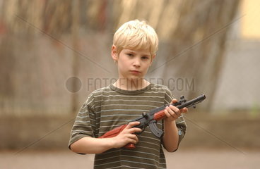 kleiner Junge spielt mit Spielzeugwaffe