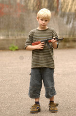 kleiner Junge spielt mit Spielzeugwaffe