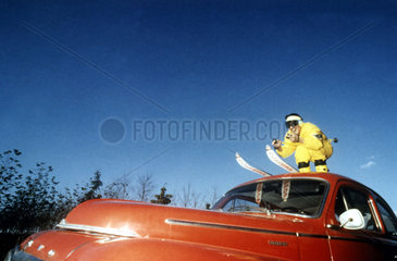 Skifahrer auf rotem Auto