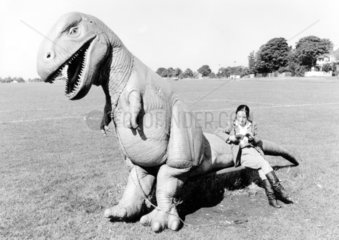 Frau sitzt auf Dino
