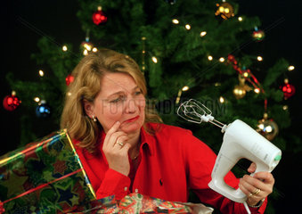 enttaeuschte Frau mit Mixer als Weihnachtsgeschenk