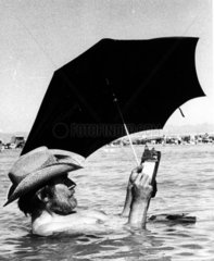 Mann mit Sonnenschirm im Wasser