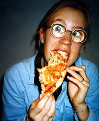 Maedchen mit dicker Brille isst Pizza
