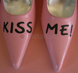 Kiss Me geschrieben auf spitzen pinken Damenschuhen