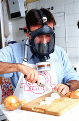 Mann mit Gasmaske schneidet Zwiebeln