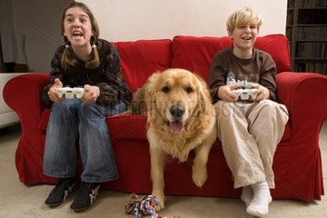 Children playing a video game and Golden Retriever on settee