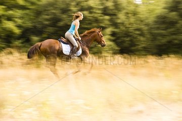 Young woman at a gallop in the dry grass France