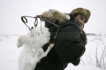 JÃ¤ger  der einen in Kanada gefangenen arktischen Fuchs auf dem RÃ¼cken trÃ¤gt