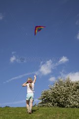Young girl flying red kite in blue sky Broadway Tower UK