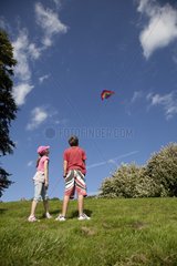 Children flying red kite in blue sky Broadway Tower UK