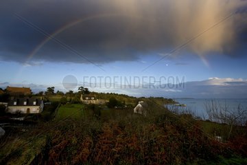Rainbow above houses on the coast Brittany France