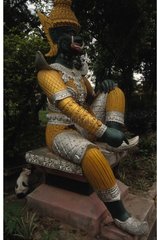 Rinnenkatze  die hinter einer Thailand -Statue sitzt