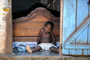 Young boy sitting at the entrance to his bedroom Madagascar